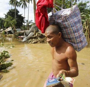 A man carries his belongings in a village hit by flash floods caused by Typhoon Washi in Iligan city, southern Philippines December 19, 2011. Disaster agencies on Monday rushed to deliver body bags, food, water, and medicine to crowded evacuation centres in the southern Philippines as officials considered digging mass graves for hundreds killed in weekend flash floods. (MNS photo)