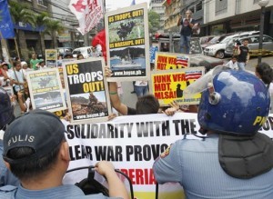Protesters hold placards in front of anti-riot policemen during a protest calling for the pullout of U.S. troops stationed in the Philippines outside the U.S. Embassy in Manila April 9, 2013. (MNS photo)
