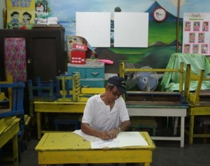 A Filipino man fills out a ballot at a classroom used as a voting precinct during mid-term elections at a school in Manila, Philippines on Monday, May 13, 2013. (MNS photo)