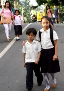 A senior elementary student guides her little brother for a long walk to reach their school at Barangay North Fairview Elementary School in Quezon City Monday (June 3,2013). (MNS photo)