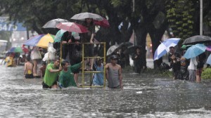 Office workers stand on top of a rolling scaffolding as they cross a flooded street at the financial district of Makati, south of Manila, Philippines on Tuesday, Aug. 20, 2013. Flooding caused by some of the Philippines' heaviest rains on record submerged more than half the capital Tuesday, turning roads into rivers and trapping tens of thousands of people in homes and shelters. The government suspended all work except rescues and disaster response for a second day. (MNS photo)