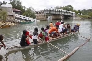 Villagers ride on a boat to cross a river after a bridge was damaged in Loon, Bohol, a day after an earthquake hit central Philippines October 16, 2013. (MNS photo)