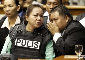 Janet Lim Napoles, wearing a bullet proof vest, listens as her lawyer Howard Areza whispers to her while Napoles attended a public inquiry at the Senate in Manila November 7, 2013. Napoles, the wife of a former Marine major, has been accused by the Department of Justice of setting up fake non-government organisations that since 2007 received lawmakers’ pork barrel funds and then routed the money back to them.