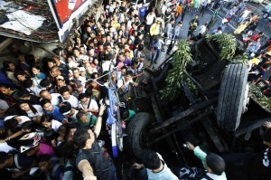 Pedestrians walk beside an overturned bus lying along a busy street at Bicutan after the bus fell off an elevated expressway and crashed into a van below in Taguig city, south of Manila December 16, 2013. At least 21 people were killed during the incident, according to the police. (MNS photo)